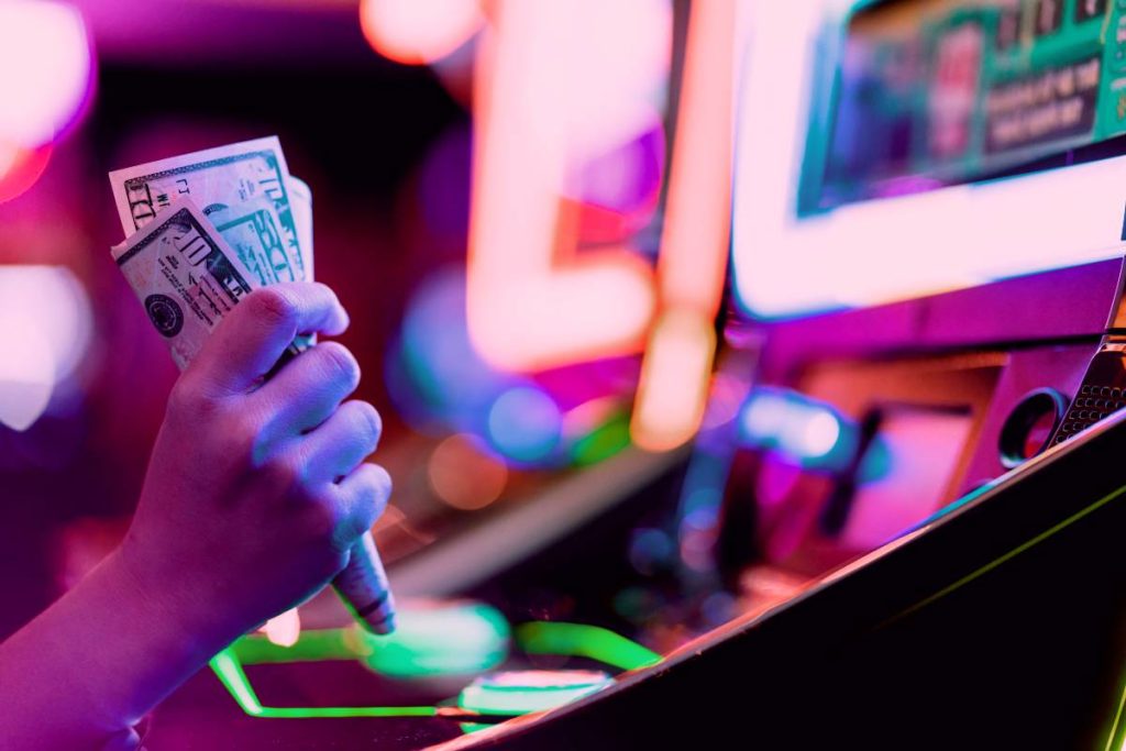 Hand with Money playing slot machine